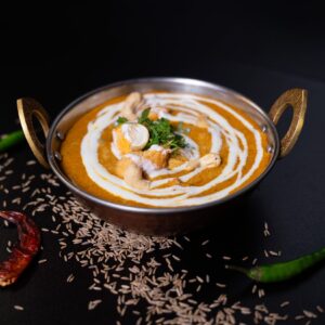 Kesudiós curry, kesudióval díszítve, egy hagyományos indiai tálban tálalva. Körbedíszítve chilivel és köménnyel.