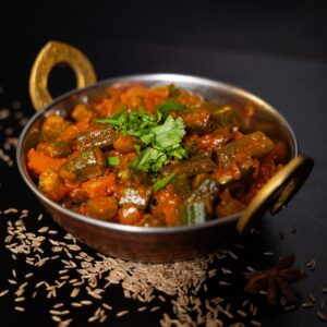 Különleges okra curry a Fusion Grillből, egy hagyományos indiai tálban tálalva, különböző fűszerekkel díszítve.