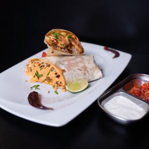 A Fusion Grill szaftos, sajtszószós Burritoja fehér tányéron tálalva salsával és tejfölös szósszal