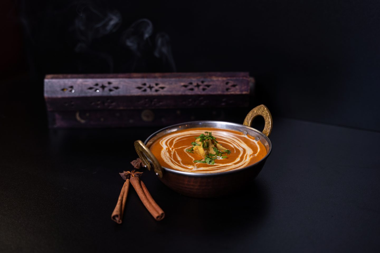 A Fusion Grillben kapható vajas csirke, két rúd fahéjjal díszítve, a háttérben egy füstölővel