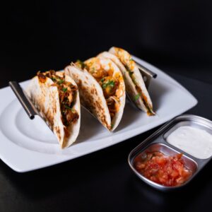 Három különböző taco egy tányéron. Egy csirkés, egy garnélás és egy zöldséges.