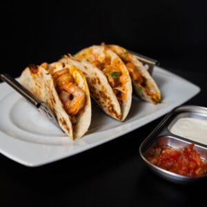 Három garnélával töltött taco salsával és tejfölös szósszal.