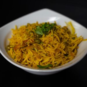 sárga, indiai basmati rizs, zöldségekkel bekeverve, egy fehér tányérban