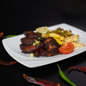 mexikói csirkeszárnyak jalapenoval és sült krumplival tálalva, chili paprikákkal díszítve