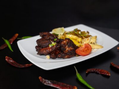 mexikói csirkeszárnyak jalapenoval és sült krumplival tálalva, chili paprikákkal díszítve